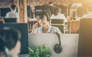 Call center worker accompanied by her team. Smiling customer support operator at work